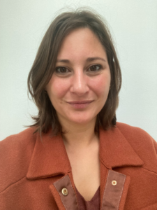 Headshot of woman in ochre jacket facing the camera